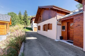 Une rue étroite bordée de bâtiments en bois, avec un chemin de gravier et de la verdure.