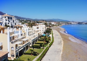 A coastal hotel with a long, narrow building, a beach, and mountains in the background. - Apartment 'Estepona Beach' with Sea View, Wi-Fi and Air Conditioning (estepona)