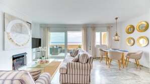 Una sala moderna con sofá, televisor y comedor con sillas y una mesa.