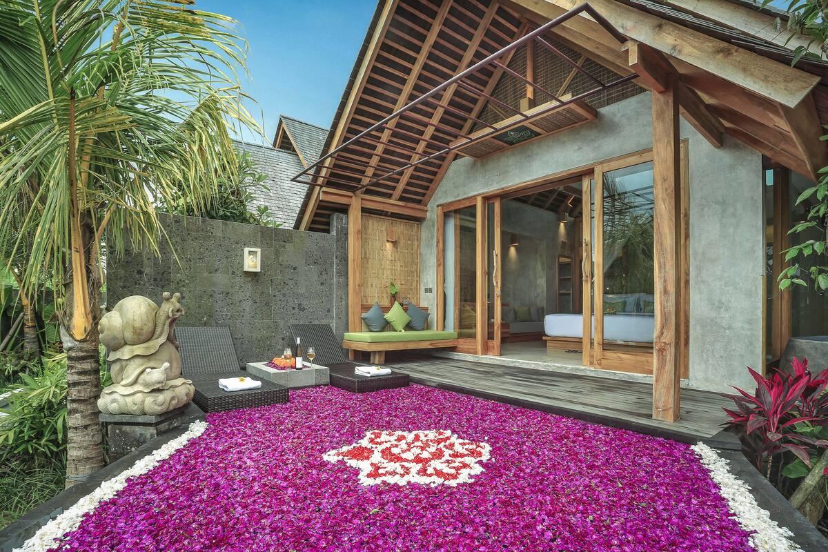 Um espaço ao ar livre moderno com uma estátua de pedra, um banco de madeira e um canteiro de flores.
