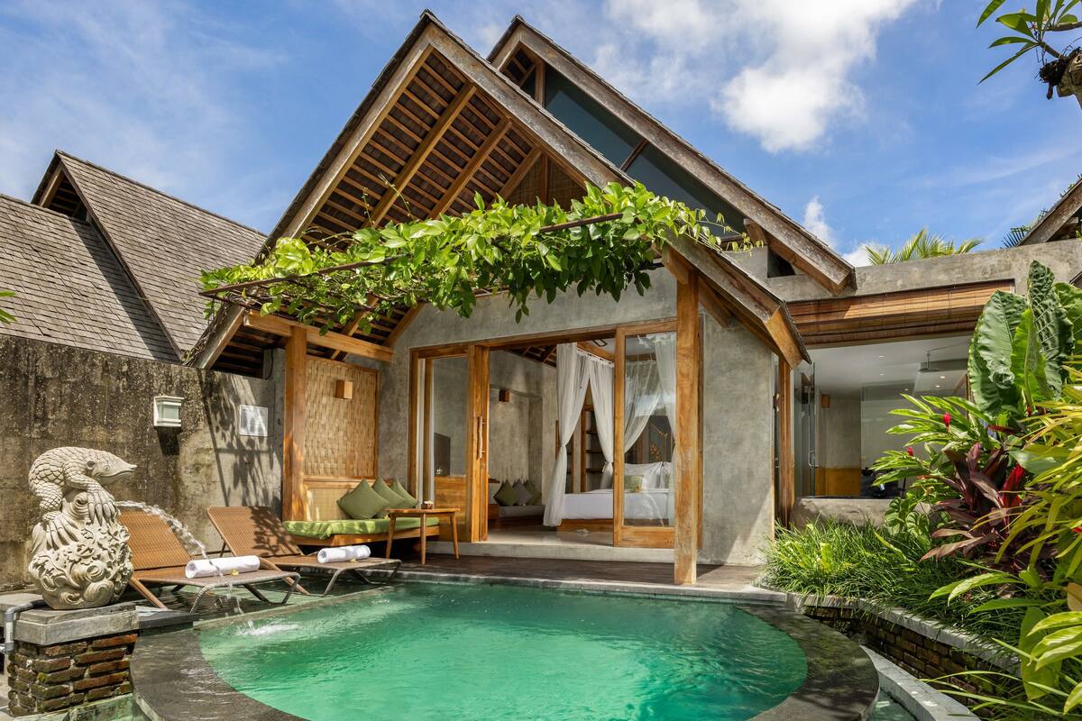 Uma villa moderna com piscina, deck de madeira e vegetação exuberante.