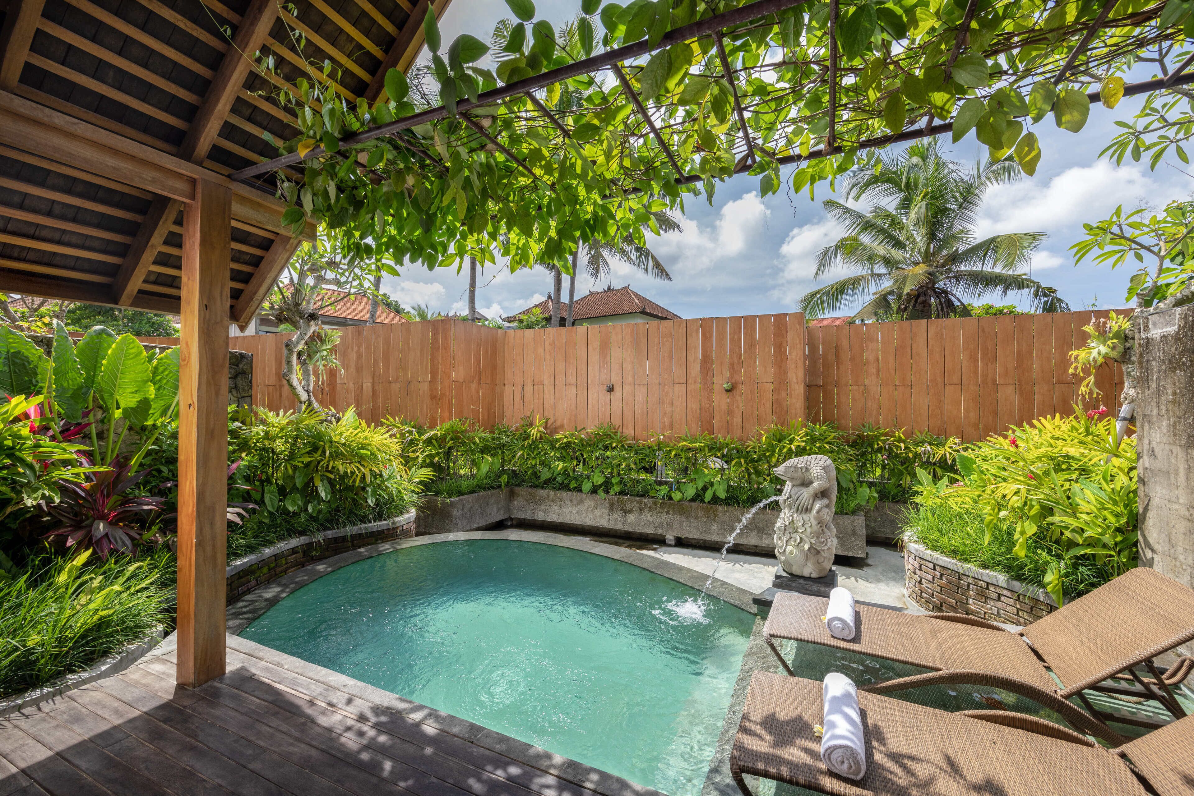A backyard with a swimming pool, wooden deck, and lounge chairs.