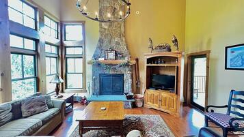 Amplia sala de estar con chimenea de piedra, muebles de madera y televisor.