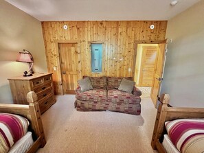 Une pièce chaleureuse avec un lambris en bois, un canapé, une commode en bois et un lit.