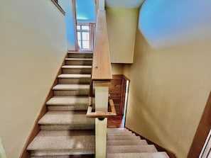 Una escalera con alfombra y barandilla de madera que lleva a una plataforma.