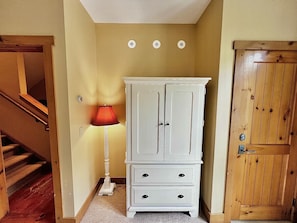 Un pasillo con un armario blanco, una puerta de madera y una lámpara roja.