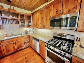 Une cuisine avec des meubles en bois, une cuisinière en acier inoxydable, un four à micro-ondes et un lave-vaisselle.