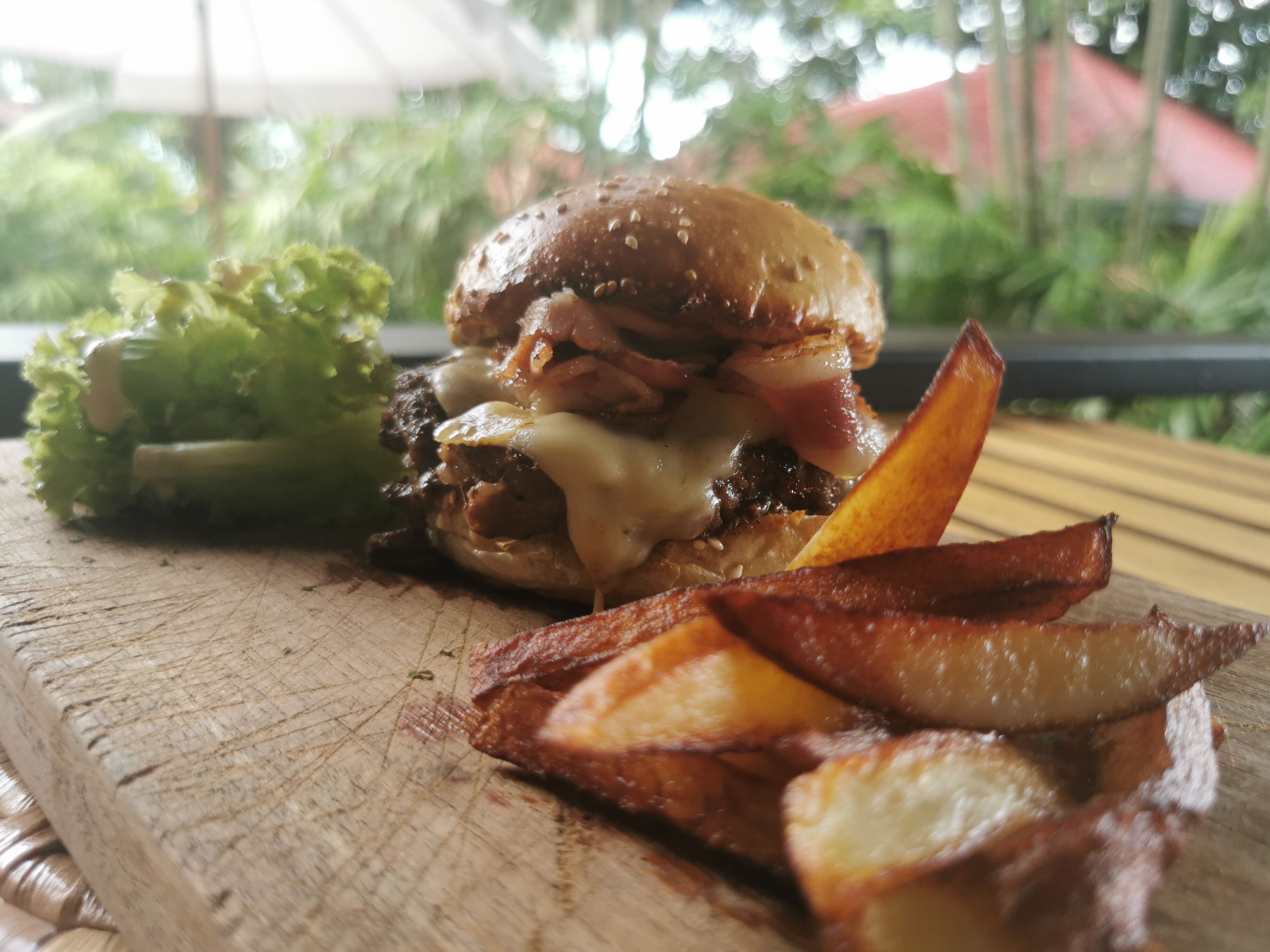 A burger with fries on a wooden cutting board.