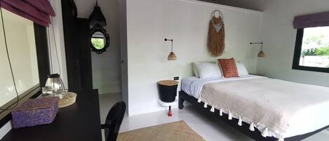 A bedroom with a bed, a desk, a chair, a window, and a ceiling fan.