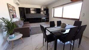 Un espai de vida modern amb zona de menjador, cuina i un gran finestral que aporta llum natural.