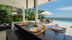 Mesa de jantar com itens de café da manhã e vista para o oceano.