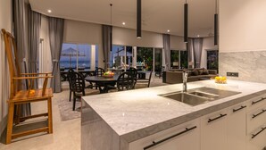 Cozinha moderna com bancada de mármore, pia embutida e área de jantar com mesa redonda e cadeiras.