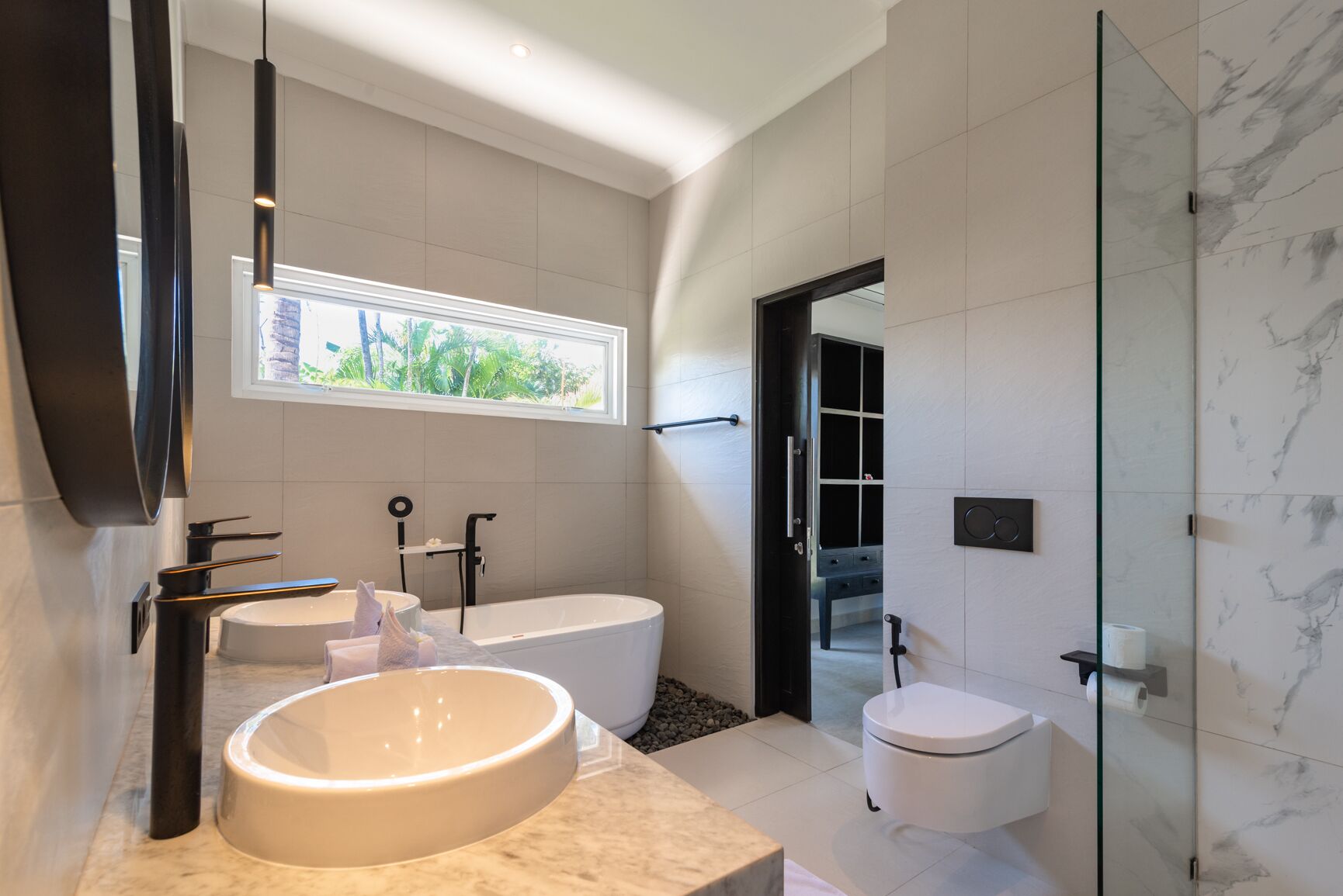 A modern bathroom with a large round sink, a freestanding bathtub, and a glass-enclosed shower area.
