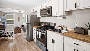 Una cucina moderna con mobili bianchi, elettrodomestici in acciaio inossidabile e un piano di lavoro in legno.