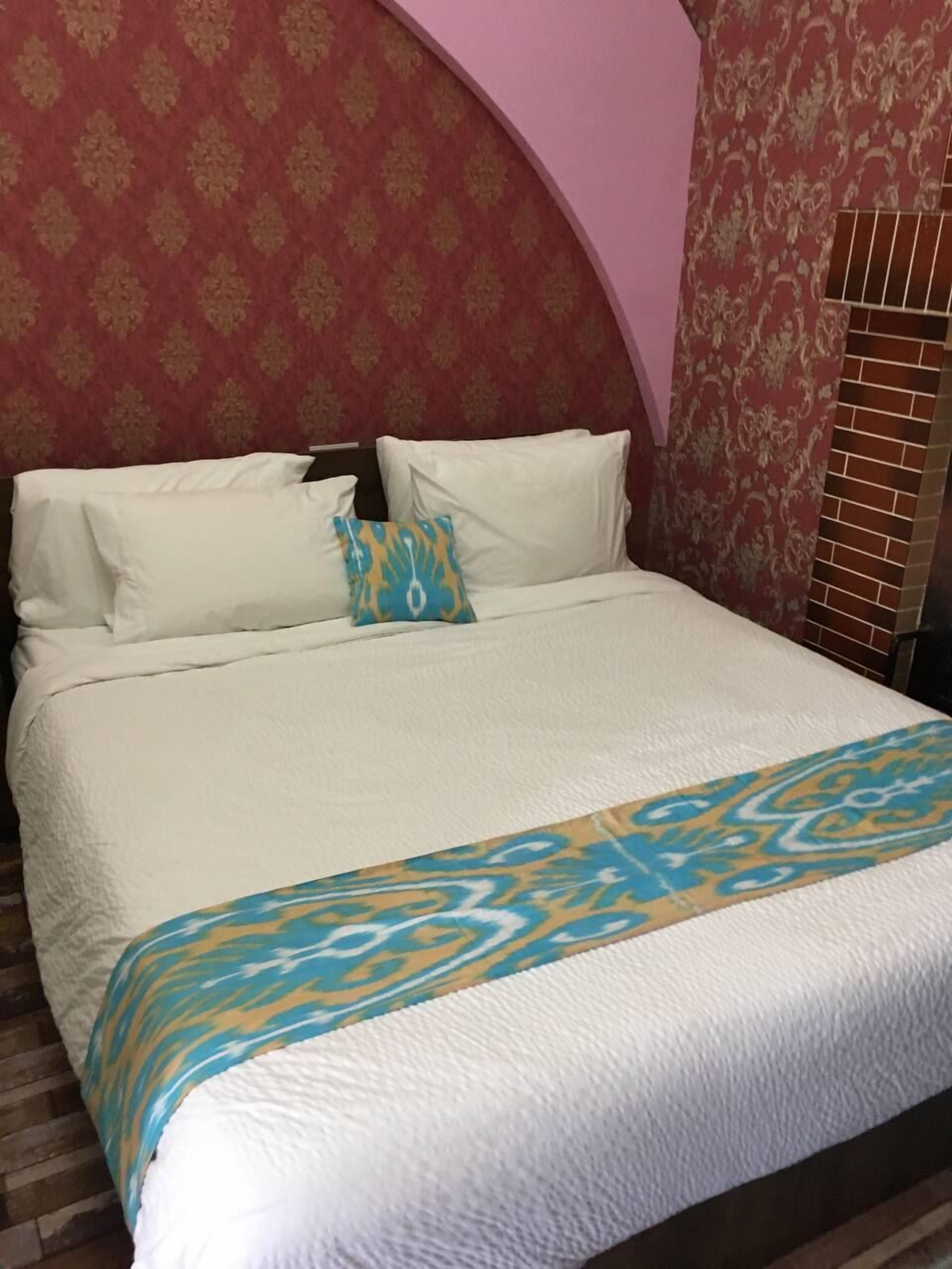 A bed with white linens and a blue and yellow patterned throw.