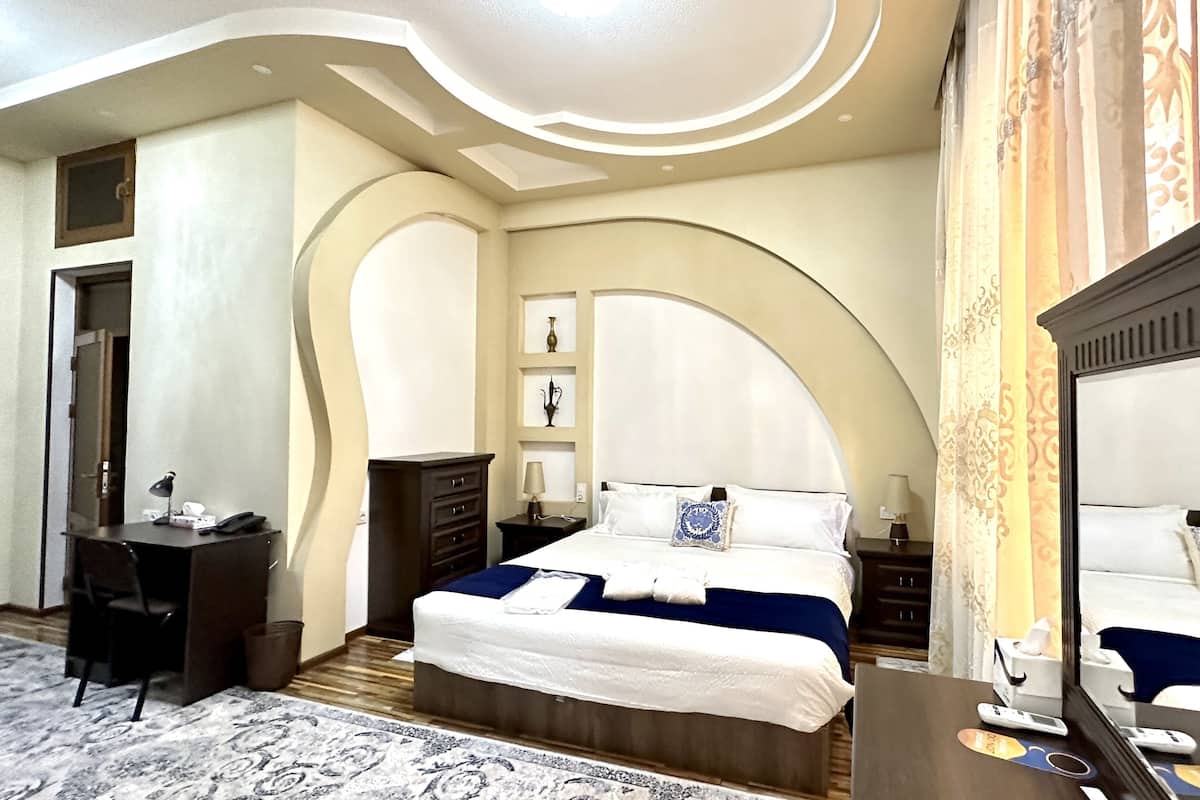 A hotel room with a large bed, a desk, and a wardrobe.
