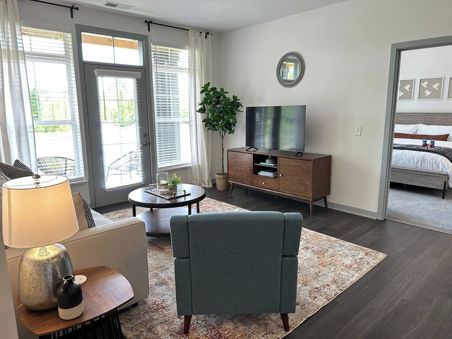 Un salon moderne comprenant un canapé, une table basse, un meuble pour la télévision et une grande fenêtre équipée de stores.