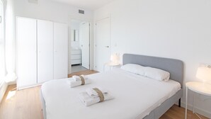 Una habitación de hotel moderna y limpia con una cama grande, mesitas de noche y un armario.