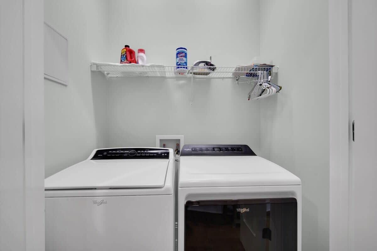 A laundry area with two washing machines and a shelf with cleaning supplies.