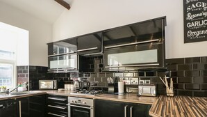 Una cocina moderna con gabinetes negros, electrodomésticos de acero inoxidable y encimera de madera.