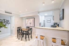 A modern kitchen with a granite countertop, white cabinetry, and a dining area with a marble floor. - Montrose Houston's Urban Charm (Houston)