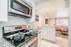 A modern kitchen with a built-in oven, microwave, and stove. There is a dining area with a sofa and a coffee table. - Montrose Houston's Urban Charm (Houston)