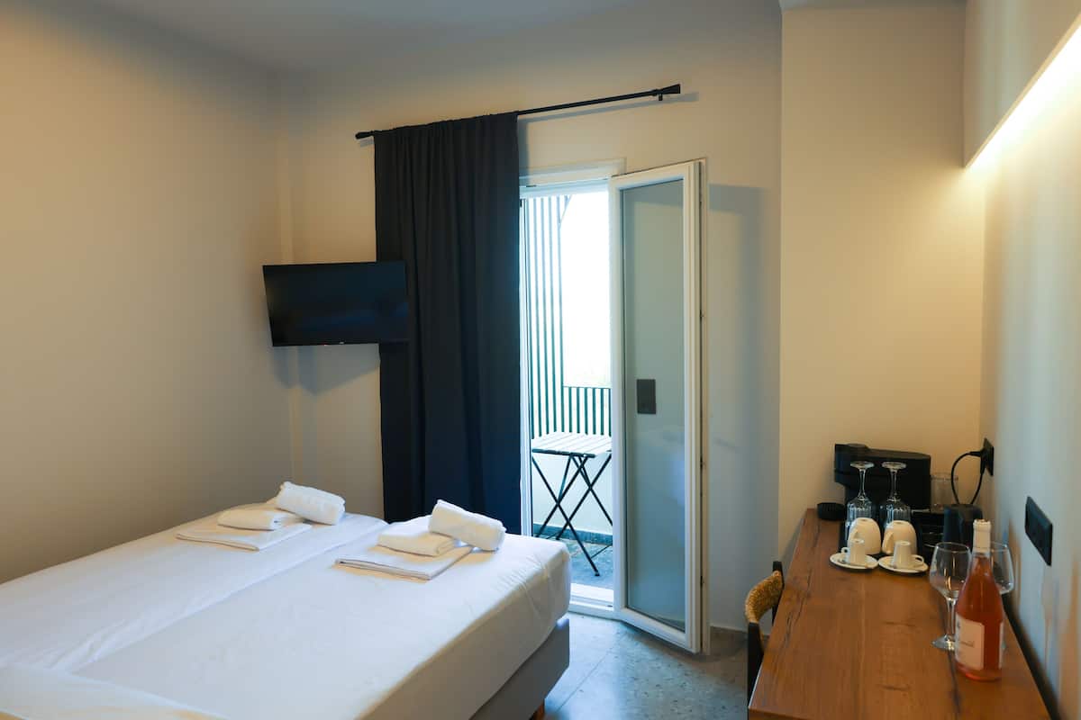 Een hotelkamer met een bed, een tafel met glazen en een fles, en een balkondeur.