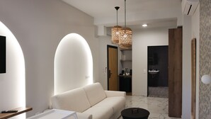Ein modernes Wohnzimmer mit einer Couch, einem Couchtisch und einem Fernseher. Eine Tür führt zu einem Badezimmer.
