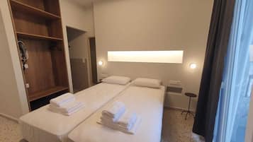 Habitación de hotel con cama doble, armario de madera, espejo, mesita de noche y ventana con cortinas.