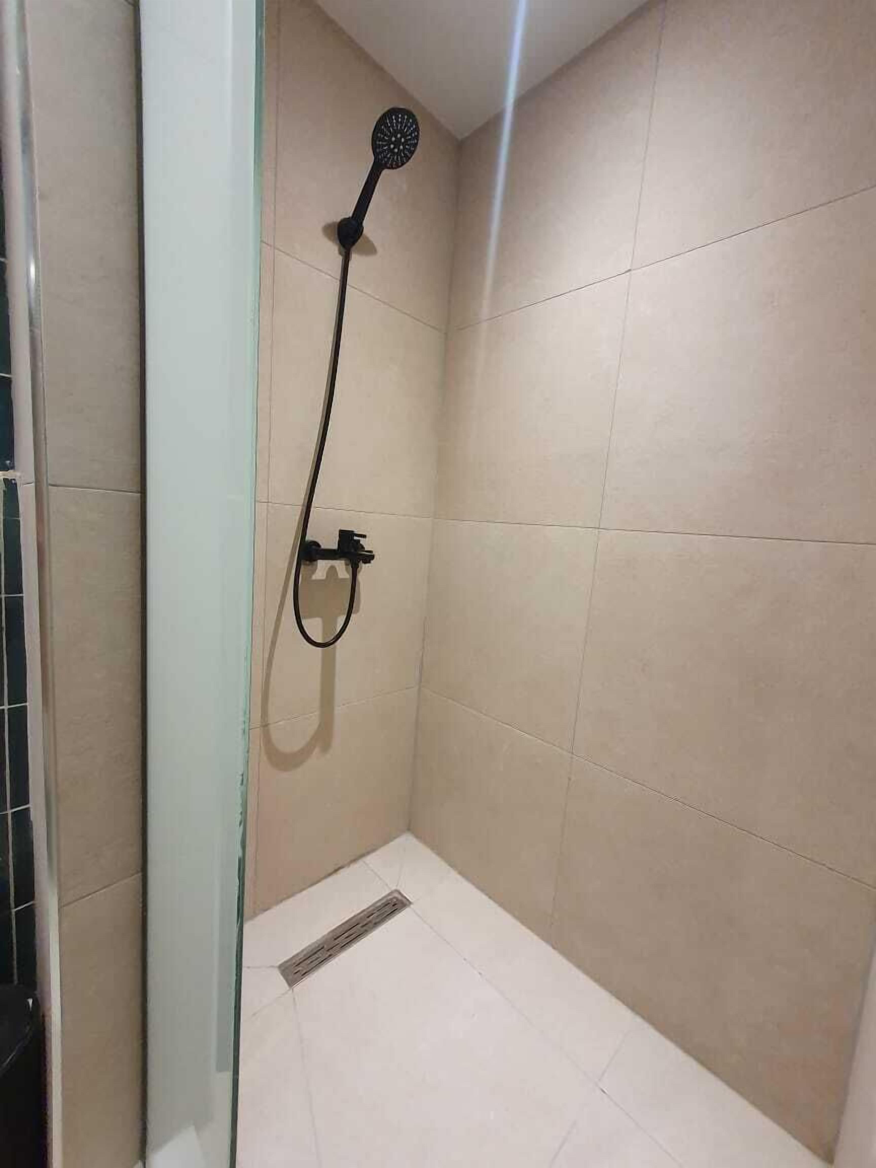Un bagno piccolo rivestito di piastrelle, con doccetta a mano e scarico a pavimento.