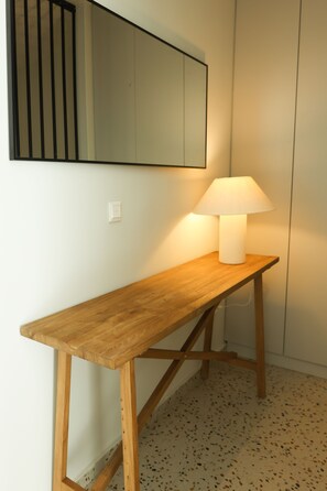 Un bureau en bois, une lampe blanche, un miroir au mur et un sol à motifs.