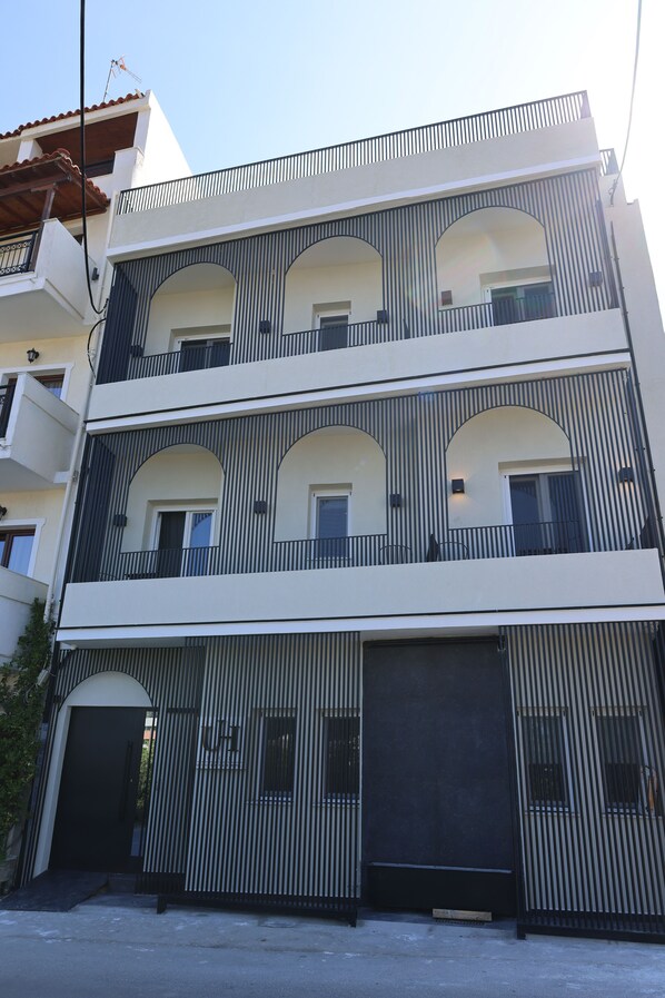 Un immeuble à plusieurs étages doté de balcons, de grandes fenêtres et d’une entrée de garage.