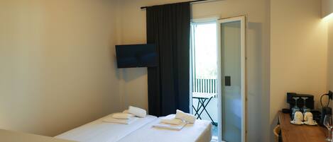 A hotel room with a bed, a TV, a coffee machine, and a table with glasses and cups.