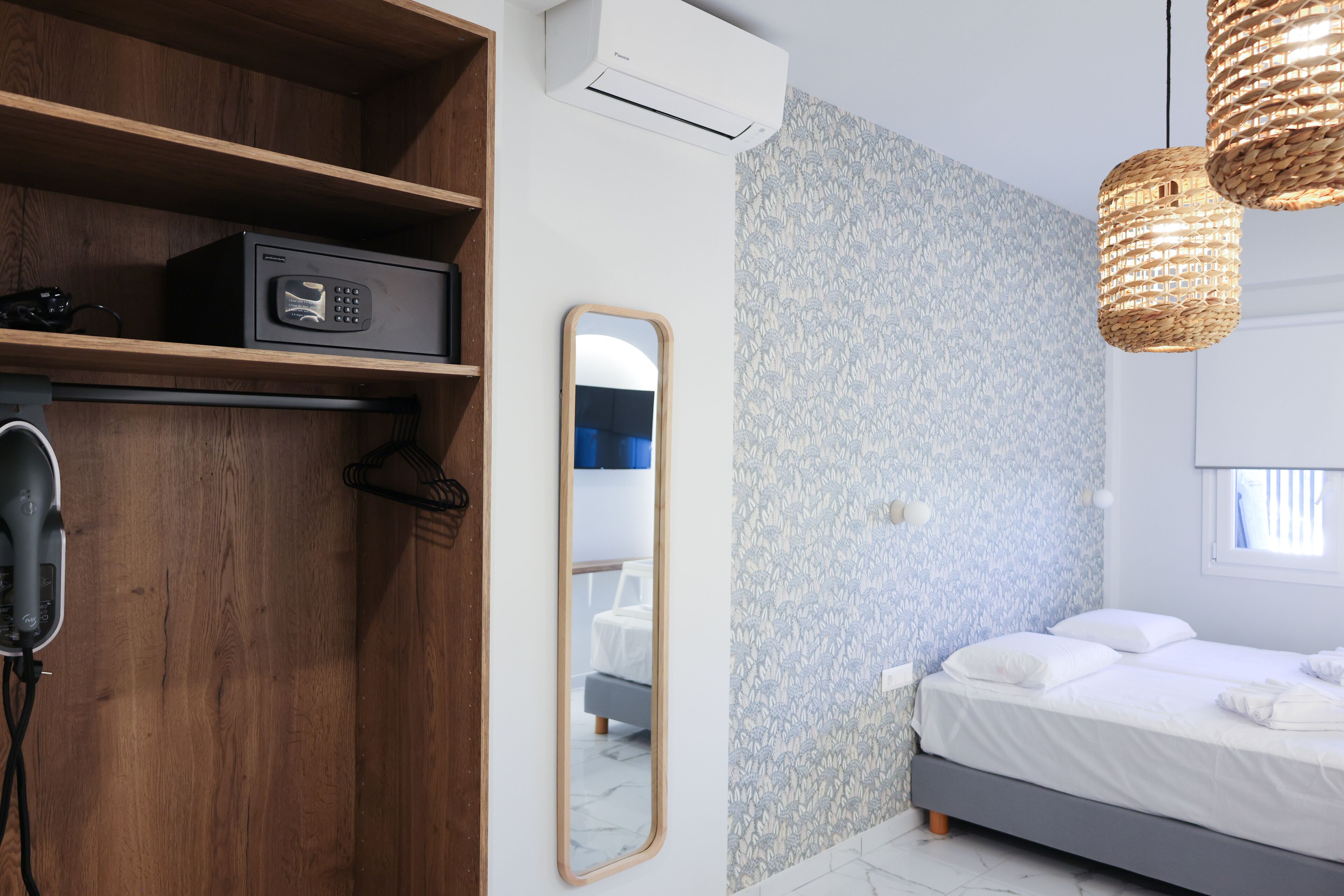 Un dormitorio moderno con cama, espejo, armario y secador de pelo.
