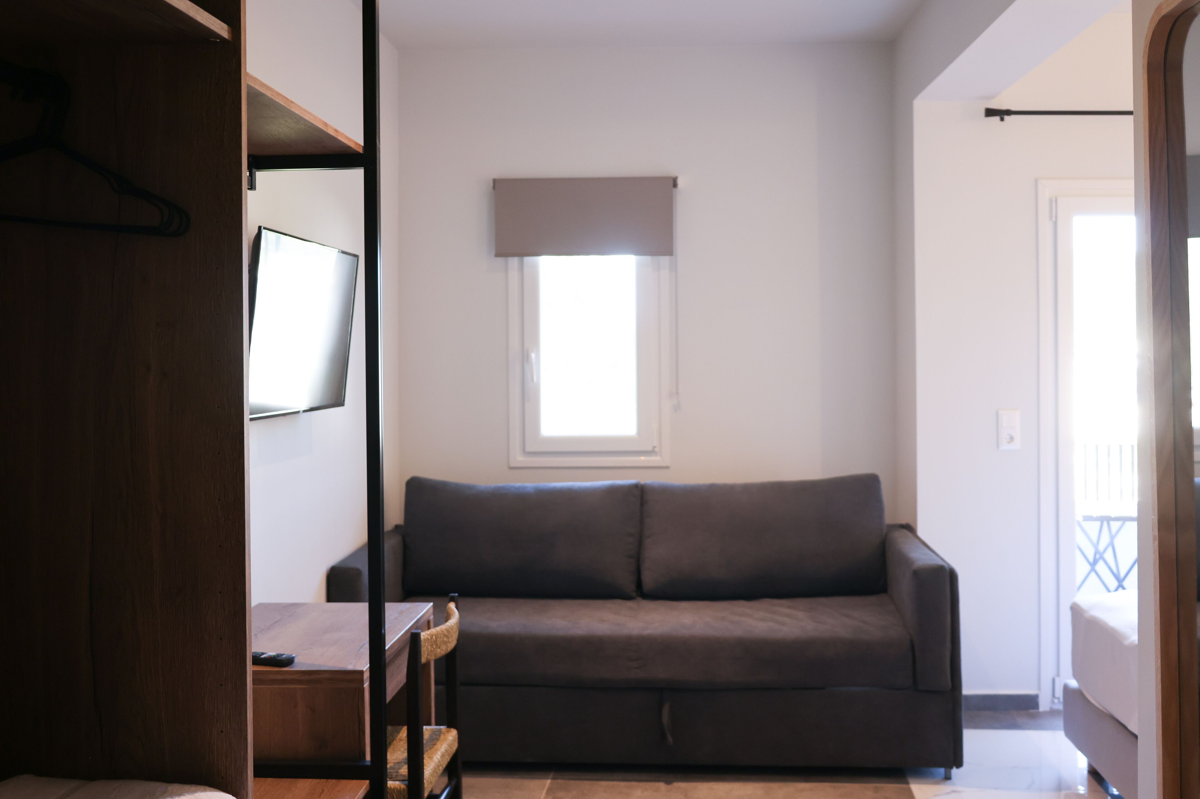 A room with a dark-colored sofa, a wooden table, and a television on the wall.