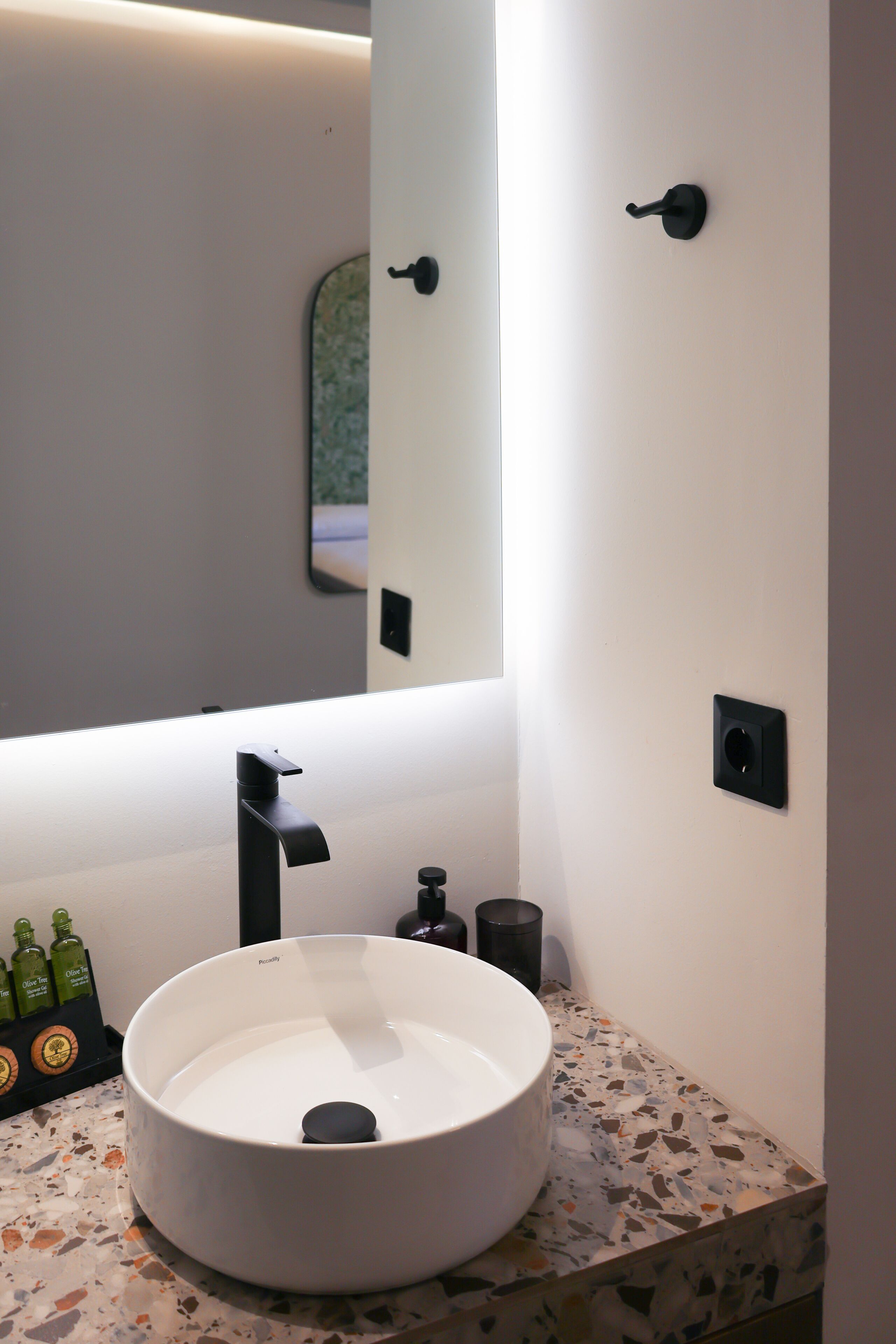 Un baño moderno con un lavamanos redondo, un espejo y un grifo de pared.