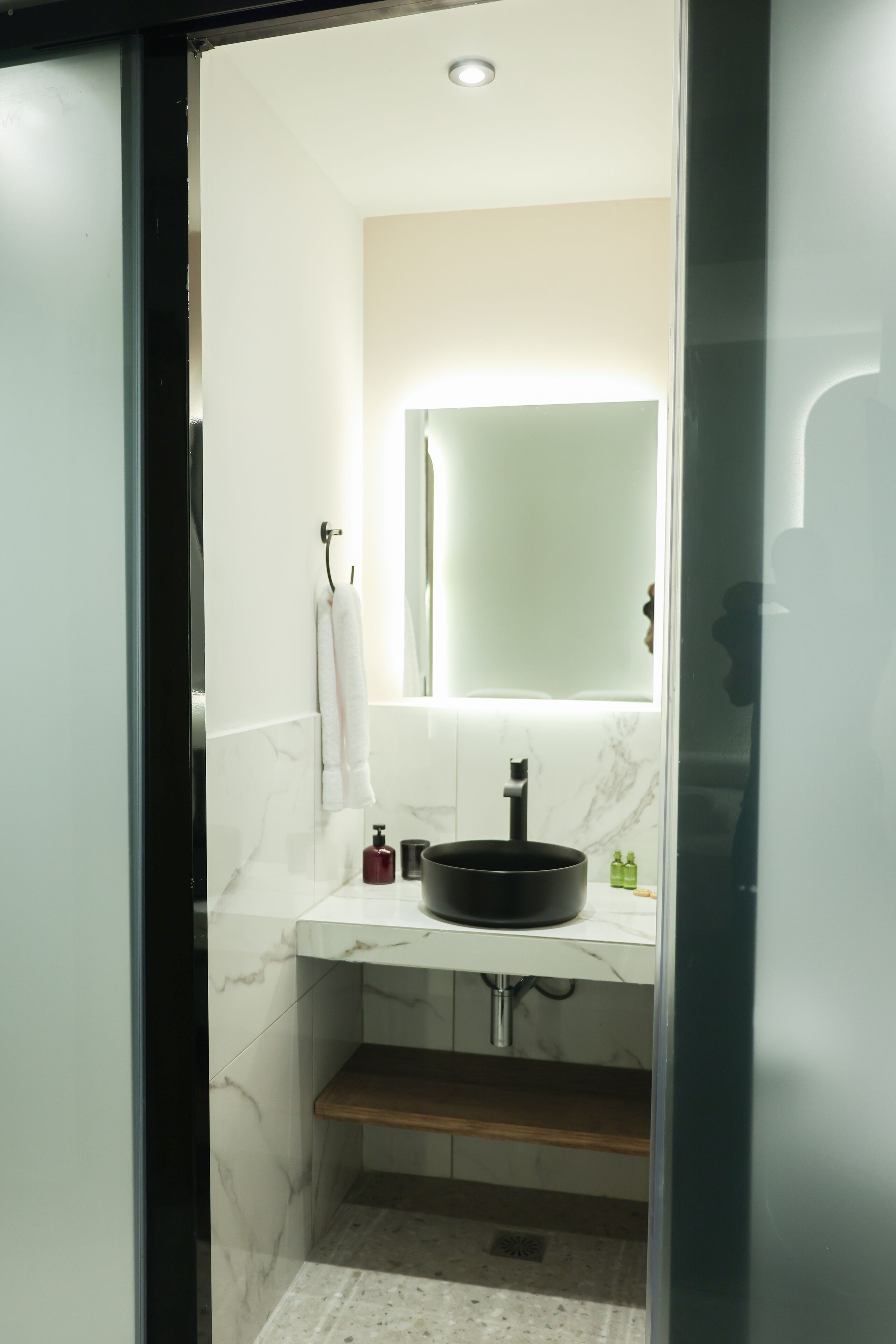 A modern bathroom with a white marble sink, a black faucet, and a mirror above it.