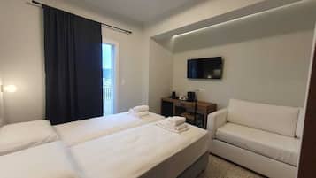 A hotel room with two beds, a sofa, a TV, and a desk.
