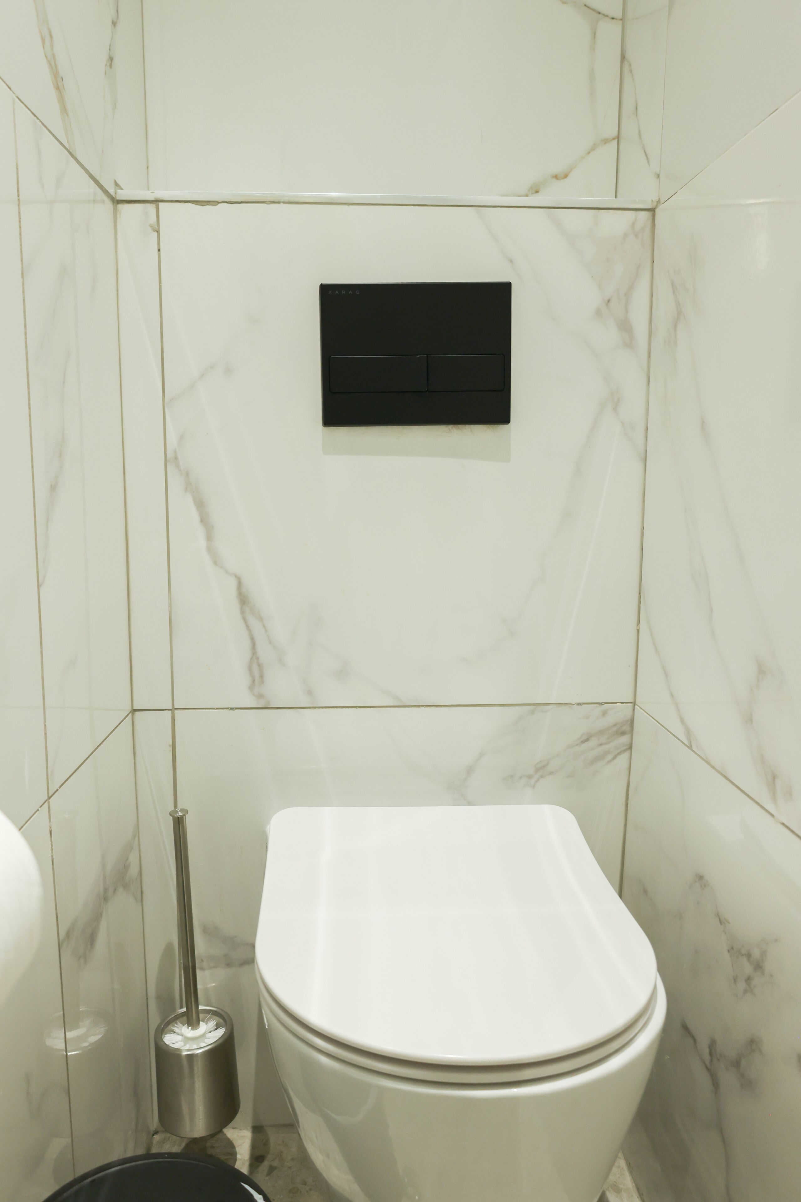 A bathroom with a white toilet, a bidet, and a wall-mounted flush handle.