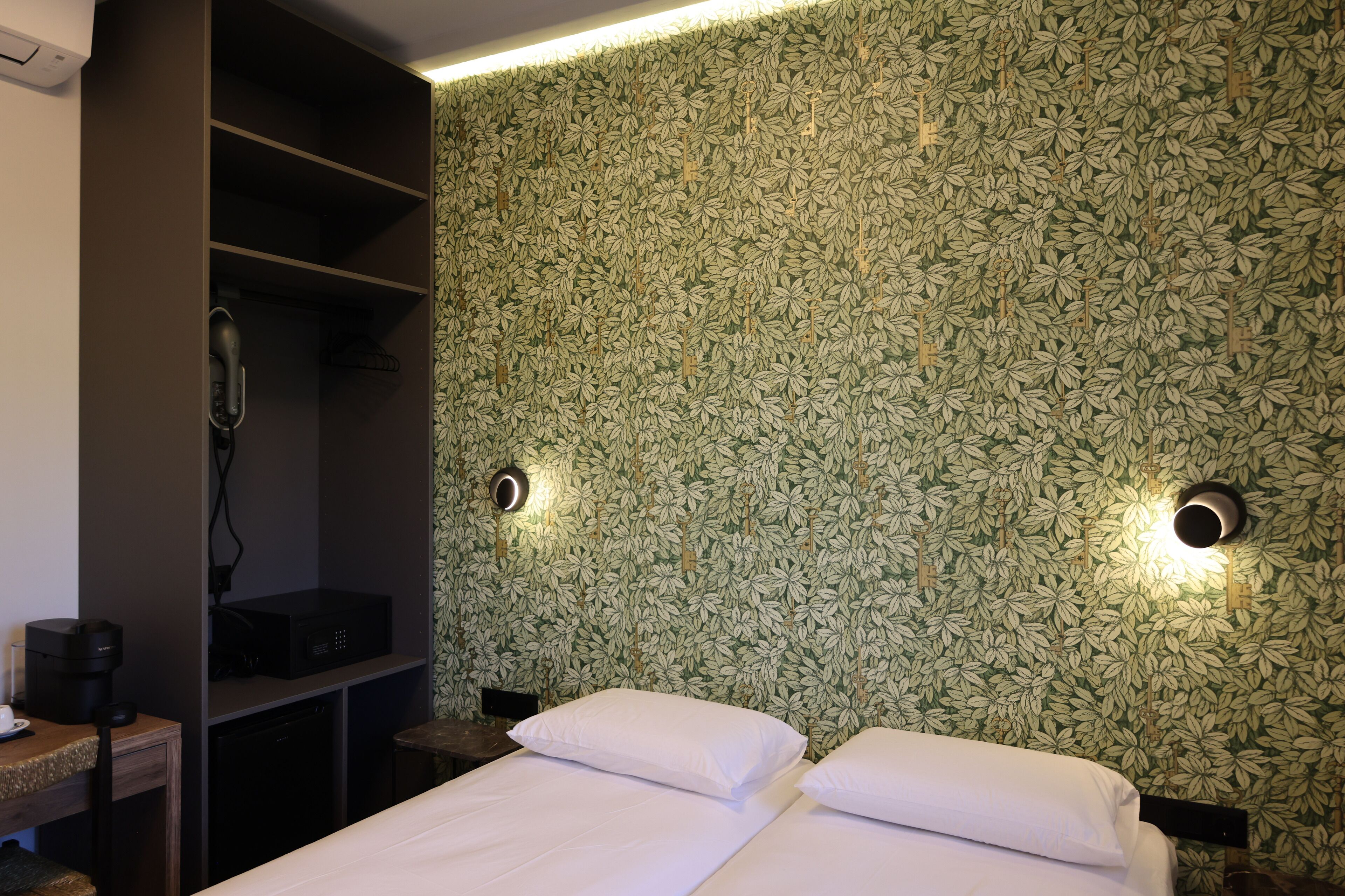 Ein Hotelzimmer mit einem Bett, einem Schreibtisch mit Kaffeemaschine und einem Kleiderschrank.