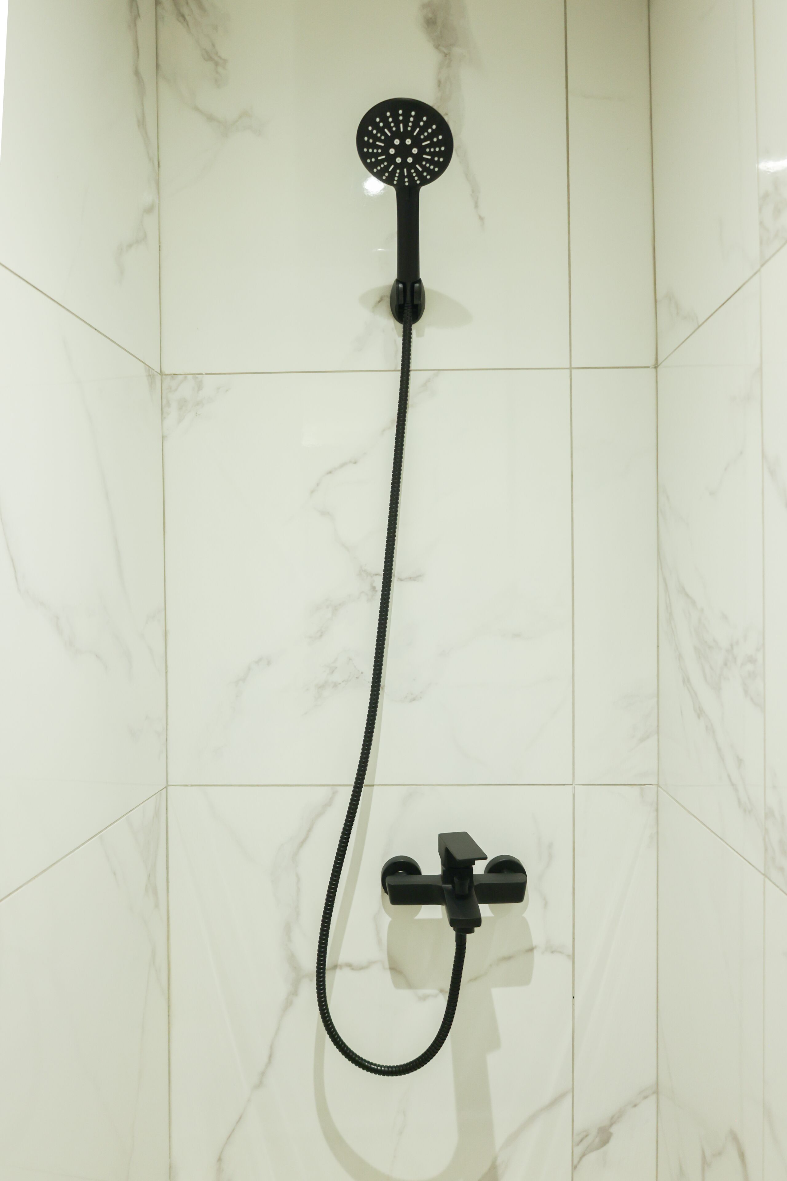A shower with a handheld showerhead and a handheld control.