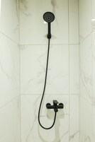 Una ducha con cabezal de ducha de mano y control manual.