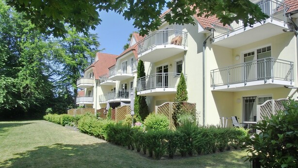 A multi-story residential building with balconies, a well-maintained lawn, and surrounding greenery. - Strandnahe 2-zimmer-fewo für 3 Personen mit Wlan (Graal-Müritz)
