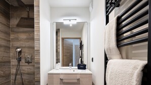 A modern bathroom with a shower, a vanity with a mirror, and a towel rack.