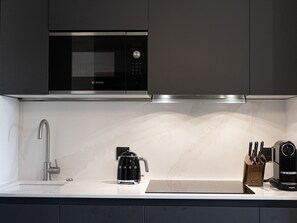 Eine moderne Küche mit einer Bosch-Mikrowelle, einem eleganten Wasserhahn, einer Smeg-Kaffeemaschine und einem Messerblock.