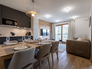 A modern kitchen with dark cabinets, a Bosch coffee machine, and a dining area with a wooden table set for four.