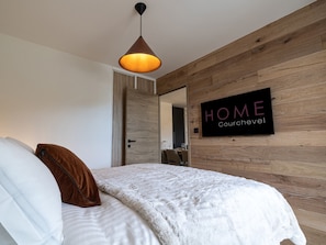 Ein modernes Schlafzimmer mit einer Holzwand, einem Bett mit weißer und brauner Bettwäsche und einem Schild mit der Aufschrift 'HOME churchavel'.