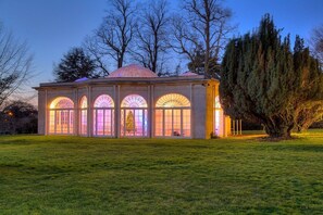 A building with large arched windows and a dome roof, surrounded by a grassy area and trees. - Barton Hall Hotel & Spa (Kettering)