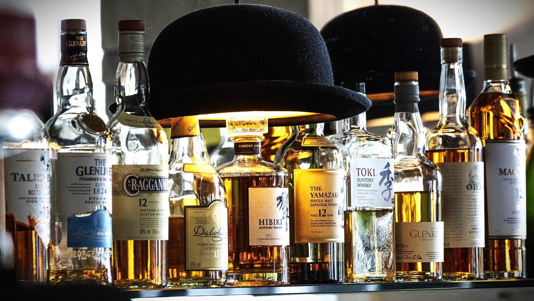 A variety of whisky bottles displayed on a shelf.