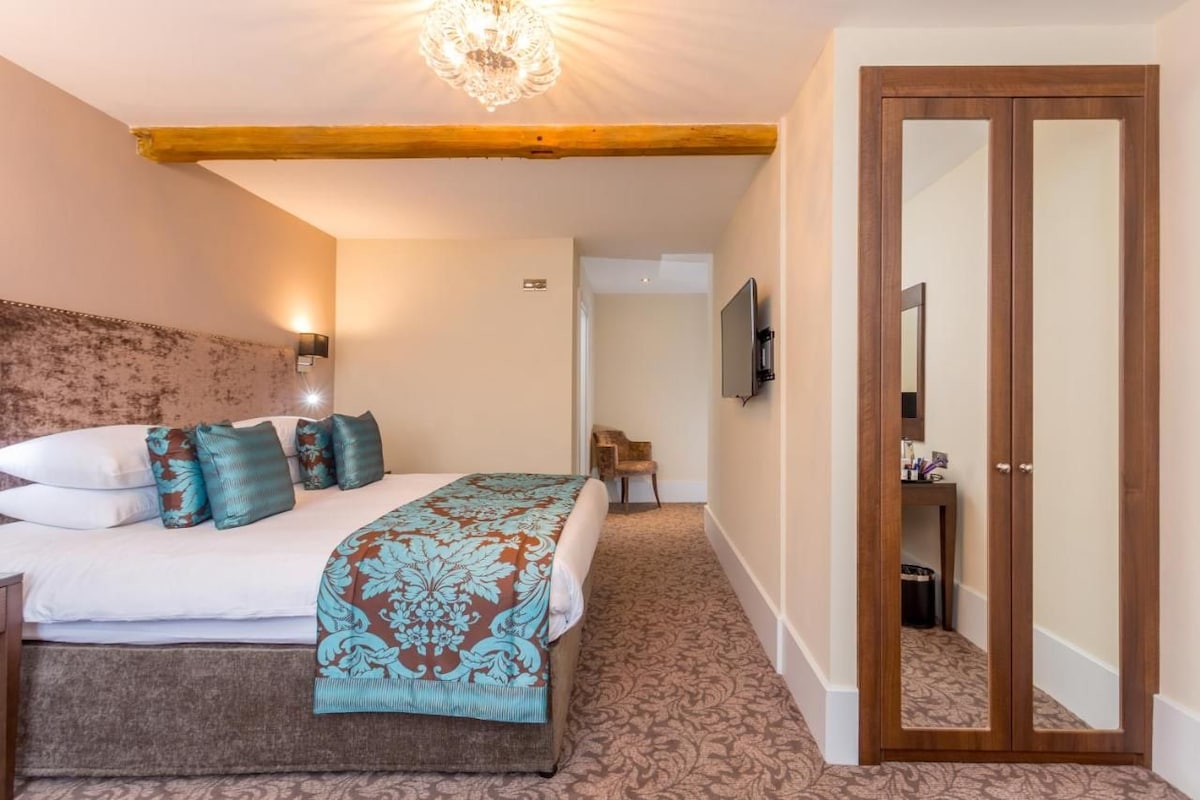 Un dormitorio con una cama, una viga de techo de madera, un televisor montado en la pared y un armario de madera.